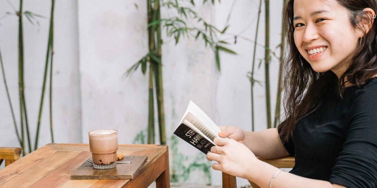 A person reading a book or newspaper, a gentle smile indicating enjoyment and lightheartedness.