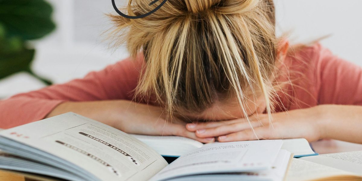 A person feeling overwhelmed while reading a challenging book.
