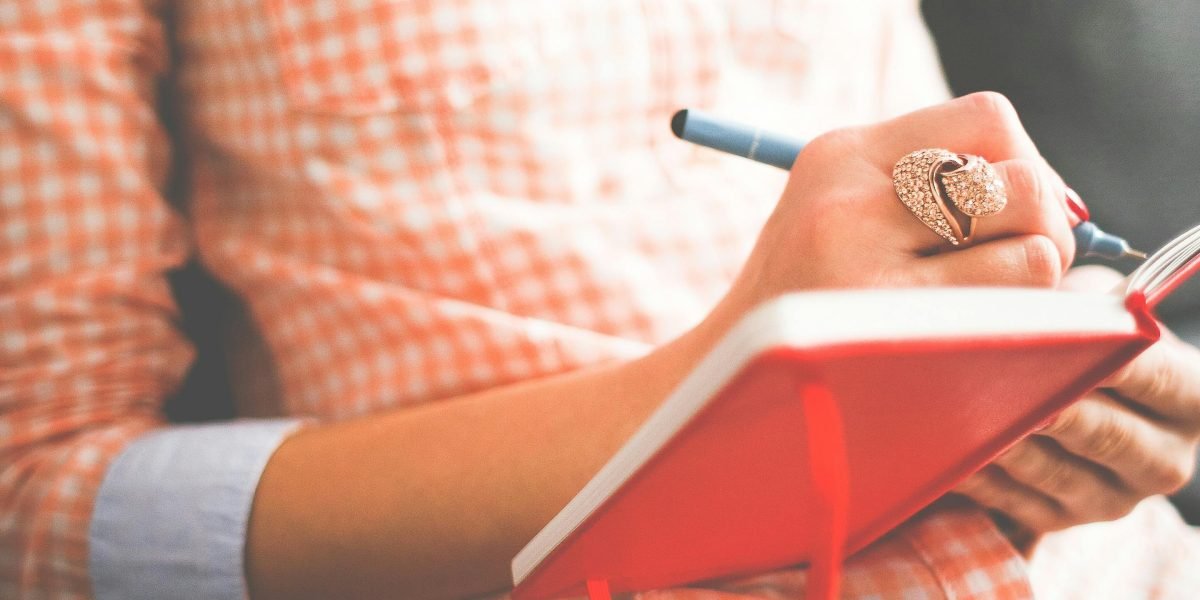 A person writing intently in a journal, symbolizing the act of self-expression and storytelling as a means of survival.